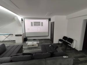 a living room with a couch and a projection screen at Gyöngy Apartmanház in Kaposszekcső