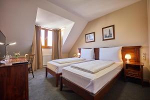 a hotel room with a bed and a desk and a bed at Pension & Restaurant PATRIOT Trnava in Trnava