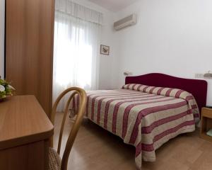 una piccola camera da letto con un letto con una coperta a righe di Hotel Perugina a Chianciano Terme