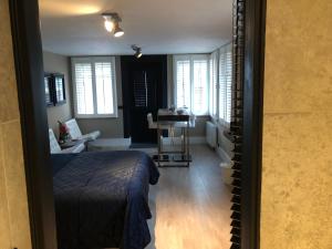 a bedroom with a bed and a living room with windows at B&B de Nieuwe Haven in Bunschoten