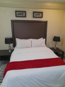 a bedroom with a large white bed with a red blanket at Pablo Guesthouse in Ermelo