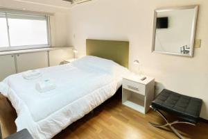 1 dormitorio con cama, espejo y silla en CORD0305 Super Lindo Departamento a metros del Obelisco en Buenos Aires