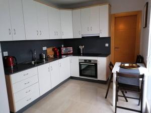 a kitchen with white cabinets and a black counter top at Atico Duque Gran Terraza Parking Free in Cartagena
