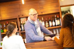 Een man in een bar die met twee mensen praat. bij Hôtel Les Genêts Bayonne in Bayonne