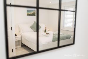 um quarto com uma cama branca e um espelho em BMTH town centre 2 min walk, 3 bed house, outside space and parking - Driftwood em Bournemouth