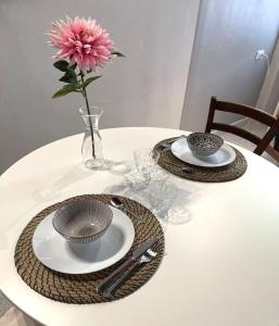 a table with two plates and a vase with a pink flower at XX Settembre Studio Apartment in Parma