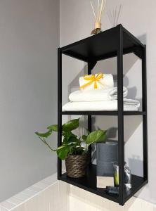 a black shelf with towels and a plant on it at XX Settembre Studio Apartment in Parma