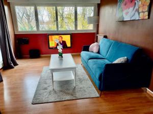 sala de estar con sofá azul y mesa en Grand 4 pièces +espace bureau à 20 min Paris !, en Créteil