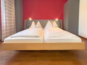 two twin beds in a room with a red wall at Hotel Rothaus Luzern & Peruvian Culinary Art in Lucerne