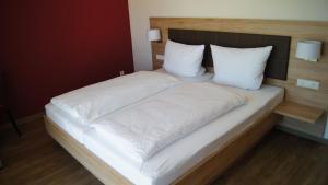 a large bed with white sheets and pillows at Gästehaus Winzerhof am Schlierbach 