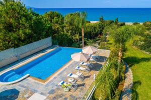 an overhead view of a swimming pool with chairs and umbrellas at Harmonia Beach Villa in Mavroli