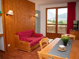 a living room with a red couch and a table at Appartement Le Dévoluy, 2 pièces, 4 personnes - FR-1-504-561 in Superdevoluy