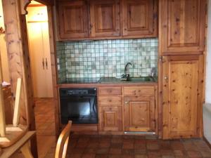 - une cuisine avec des placards en bois, un évier et une cuisinière dans l'établissement Appartement Samoëns, 3 pièces, 4 personnes - FR-1-629-52, à Samoëns