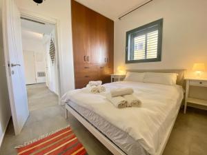 a bedroom with a large white bed with towels on it at Lapin 9 - By Beach Apartments TLV in Tel Aviv