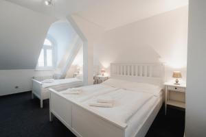 a white bedroom with a large white bed and two tables at Penzion Dvořákova in Brno