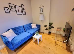 ein blaues Sofa im Wohnzimmer mit einem Tisch in der Unterkunft Oxford Gardens Apartments in London