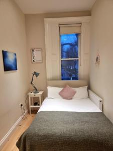 a bedroom with a white bed with a window at Oxford Gardens Apartments in London