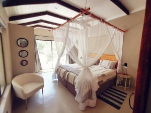 a bedroom with a canopy bed and a chair at Ostrich Hide in Marloth Park
