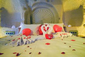 Una cama en una habitación con corazones y globos. en Babili Cappadocia Cave Hotel, en Nevşehir