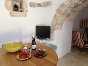 a table with wine glasses and a television in a room at Mille e un Trullo in Ostuni