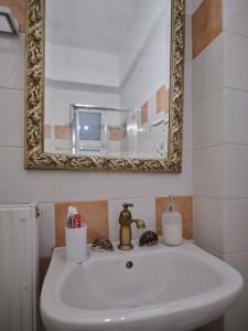 een badkamer met een witte wastafel en een spiegel bij comfort apartment in Tripolis