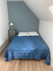 1 dormitorio con 1 cama con manta azul en sejour paisible au coeur du morbihan, en Pluvigner