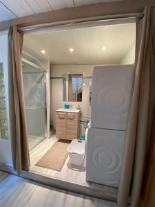 ein Bad mit einer Dusche und einem Kühlschrank. in der Unterkunft sejour paisible au coeur du morbihan in Pluvigner