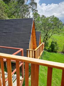 a cabin with a deck and a black roof at Glamping El Reencuentro in Machachi