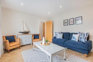 ein Wohnzimmer mit einem blauen Sofa und Stühlen in der Unterkunft The Bolt Hole -Luxury 3 bed cottage with hot tub! Silverdale in Silverdale