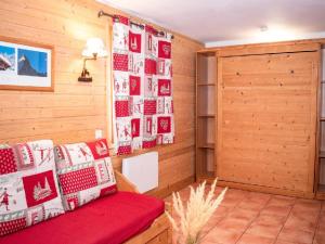 a room with a red couch and a wall with pictures at Studio 4 Pers. avec Balcon, Résidence Les Chalets de Praroustan, Pra Loup 1500 - FR-1-504-367 in Uvernet-Fours +5 photos