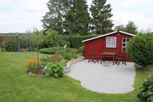 a red shed with a picnic table and a playground at Ferienwohnung im roten Haus in Stahlbrode