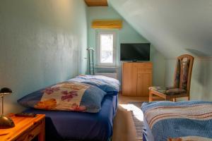 Schlafzimmer mit einem Bett, einem TV und einem Stuhl in der Unterkunft Ferienwohnung Seestraße in Lubmin