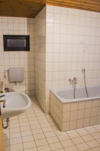 a white tiled bathroom with a tub and a toilet at Ferienhaus Seilerbahn 17 in Vallendar
