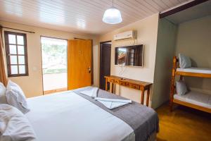 1 dormitorio con cama, escritorio y ventana en VELINN Pousada Praia do Perequê, en Ilhabela