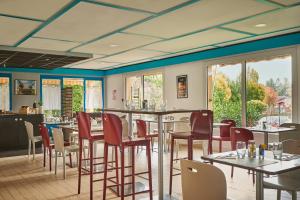 a restaurant with tables and chairs and windows at Kyriad Direct Epinal in Épinal