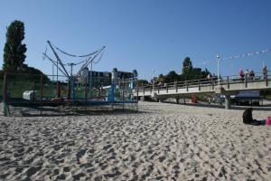 uma praia arenosa com um parque infantil e uma ponte em Bungalow Mandy em Zinnowitz