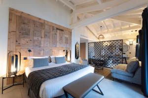 Cette chambre comprend un grand lit et une chaise. dans l'établissement L'Anderenis Boutique Hôtel, à Andernos-les-Bains