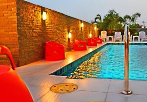 a swimming pool with red chairs next to a brick wall at Dwella Suvarnabhumi in Lat Krabang