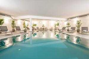 a pool in a hotel with chairs and tables at AlpenParks Hotel & Apartment Alpendorf in Sankt Johann im Pongau