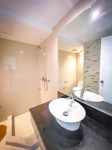 ein Badezimmer mit einem weißen Waschbecken und einer Dusche in der Unterkunft Lovely 1BR Loft in BGC Golf View in Manila