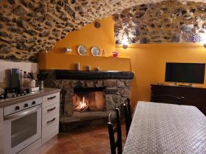 La Casa sull' Altopiano Mountain Lake Iseo hospitality في Bossico: مطبخ مع موقد مع طاولة وتلفزيون