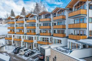 an apartment building with cars parked in a parking lot at Ski- & Sonnenresort Alpendorf by AlpenTravel in Sankt Johann im Pongau