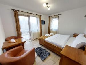 a bedroom with a bed and a chair and window at Casa Calea Haiducilor in Sohodol