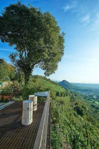 a wooden platform with a table and a tree on a hill at Rustico Costa D'oro in Farra di Soligo