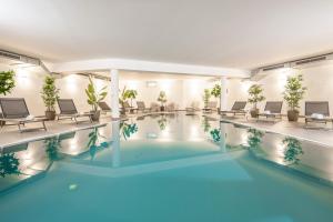 a pool in a hotel with chairs and tables at Hotel Alpendorf Ski- & Sonnenresort by AlpenTravel in Sankt Johann im Pongau