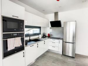 uma cozinha com armários brancos e um frigorífico de aço inoxidável em Casa Erbozeta by LovelyStay no Funchal