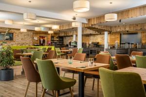 a restaurant with wooden tables and green chairs at Hotel Alpendorf Ski- & Sonnenresort by AlpenTravel in Sankt Johann im Pongau
