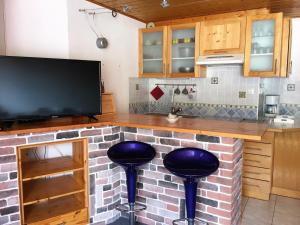 eine Küche mit zwei Barhockern und einem TV in der Unterkunft Appartement La Joue du Loup, 2 pièces, 7 personnes - FR-1-504-76 in Le Dévoluy