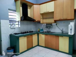 una cocina con armarios de madera y encimeras verdes en Ngio Batu Pahat Homestay, en Batu Pahat