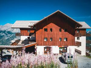 un grand bâtiment en bois avec des montagnes en arrière-plan dans l'établissement Appartement Puy-Saint-Vincent, 3 pièces, 6 personnes - FR-1-504-145, à Puy-Saint-Vincent